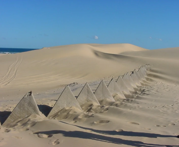 several pieces of metal fencing are attached to sand dunes