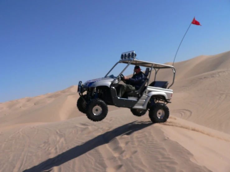 the man is riding on the large buggy in the desert