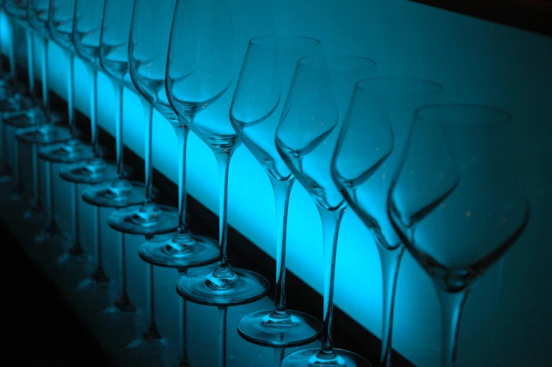 many champagne glasses lined up in front of a white wall