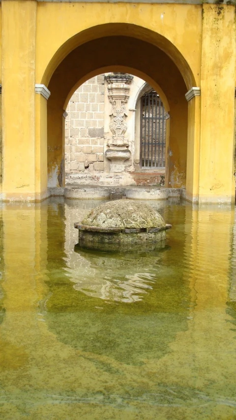 a yellow water filled courtyard has a stone planter