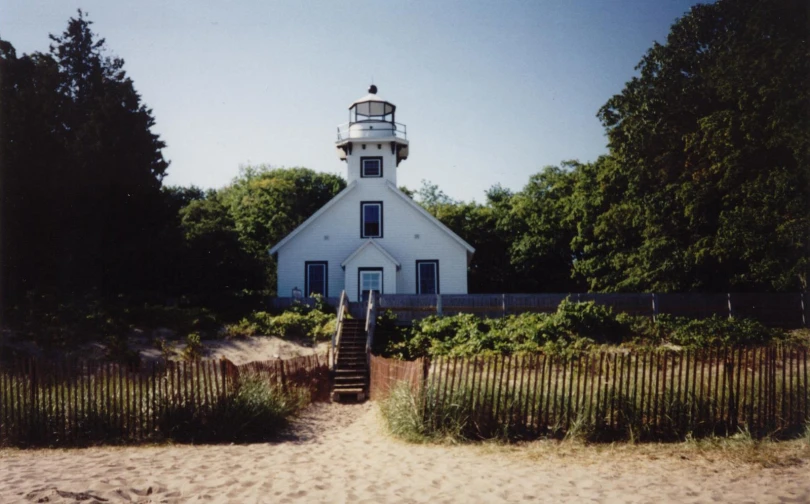 a white house with a red and black lighthouse at the top