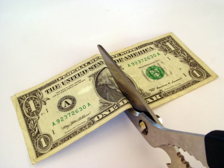 a pair of scissors  through the ends of a money bill