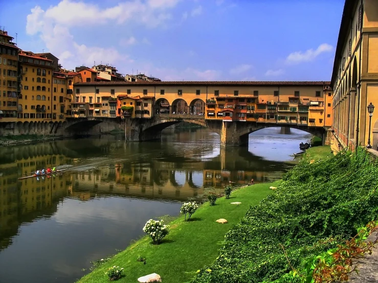 a bridge over a river near some buildings and plants