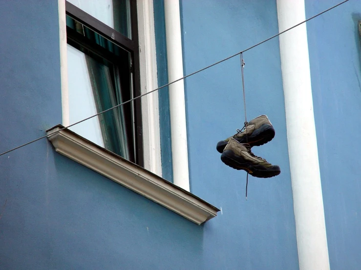 an older pair of shoes hanging by a rope from the side of a building