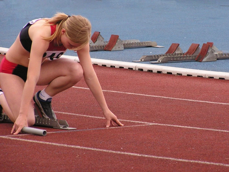 a woman is squatted down on a track