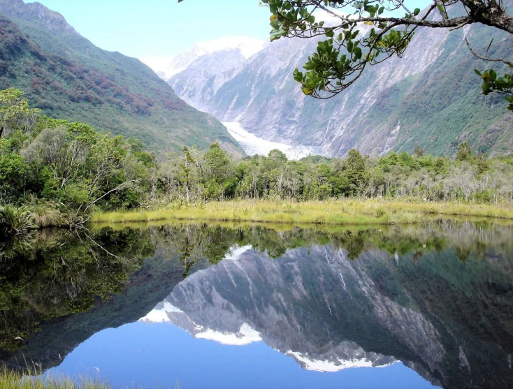 a river is surrounded by mountains and grass