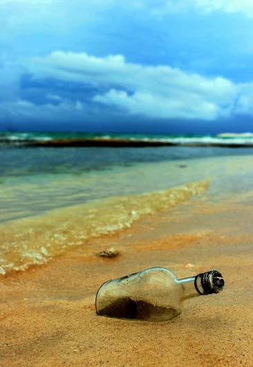 a bottle on the beach with waves coming in