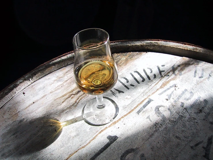 a glass of wine sitting on top of a barrel