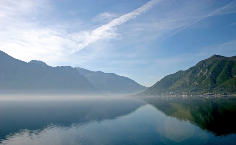 foggy water with a lake in the foreground and a mountain range beyond