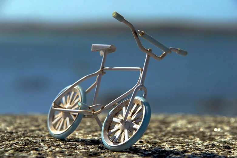 a small metal bicycle is placed in the gravel