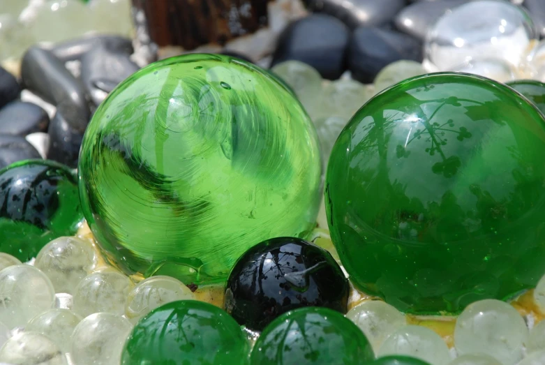 green marbles on top of each other next to a black ball