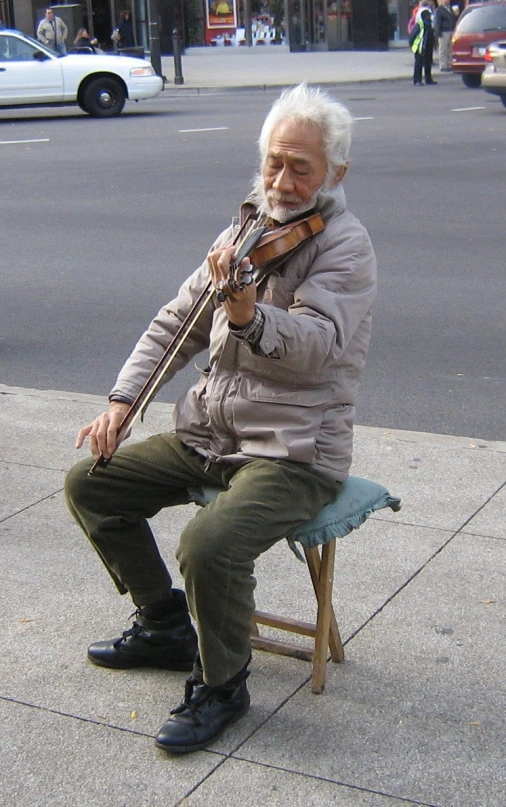 a man holding a violin while sitting on top of a bench