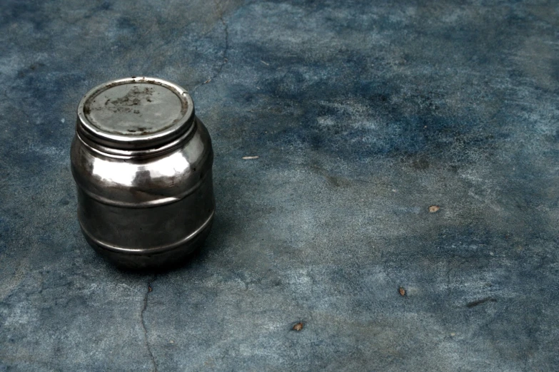 an empty metal can lying on concrete