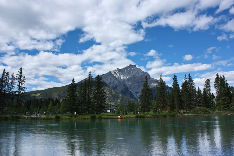 a mountain sits above a lake and surrounded by pine trees