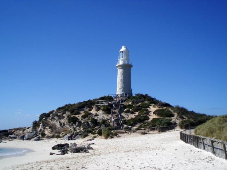 the white lighthouse is on top of a sand hill