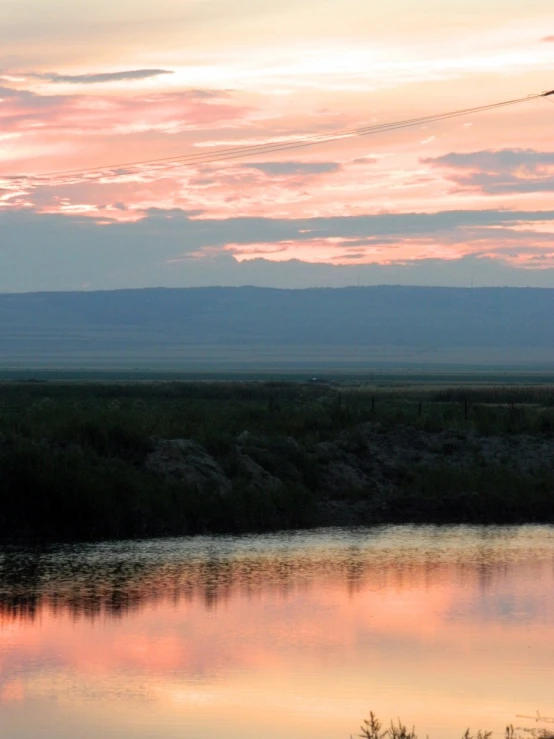 a man is fishing on the river with his horse at dusk