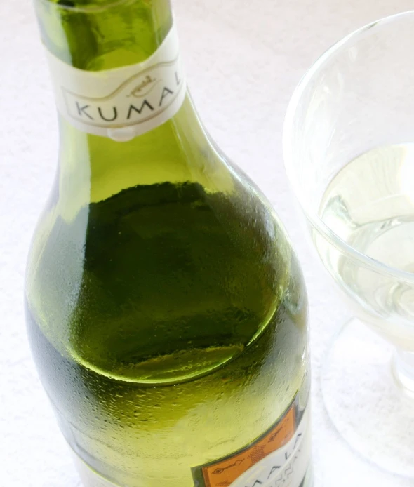 wine bottle and wine glass on table next to white cloth