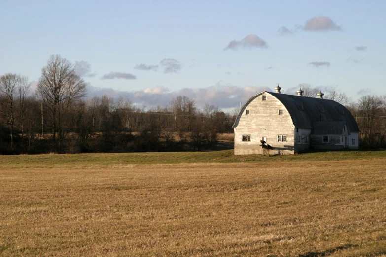 a large white barn in a large field