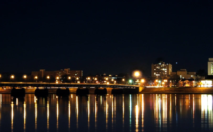 a city sits near the river and its reflection in the water