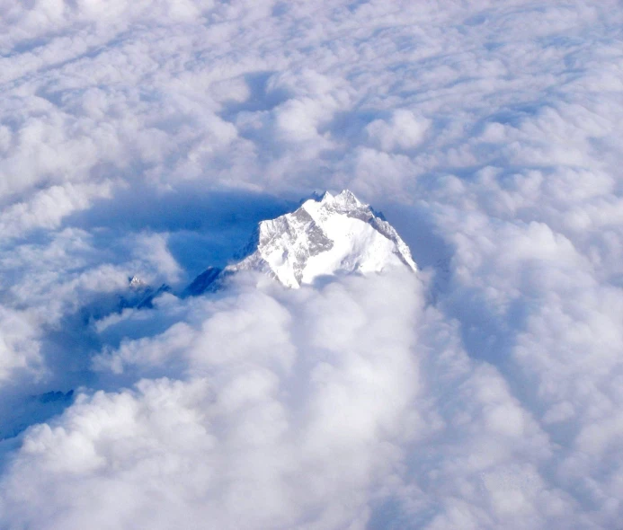 the sky is full of white clouds surrounding the peak