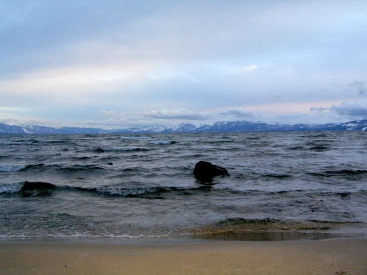 a body of water near the shore with mountains in the background