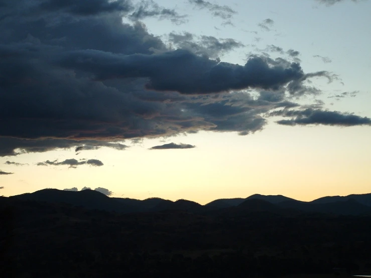 a beautiful sunset over some mountains and a lake