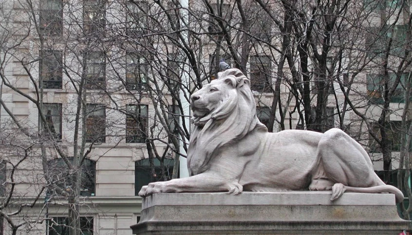 large sculpture of a lion on pedestal in front of building