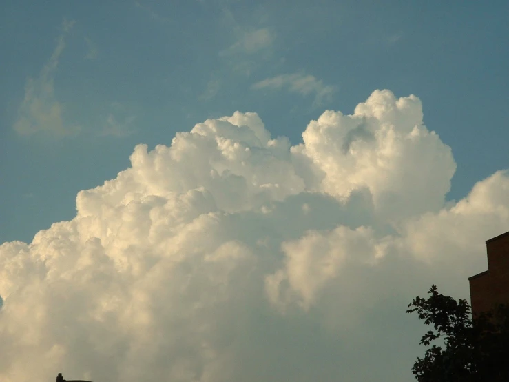 a very large fluffy cloud is in the sky above a building