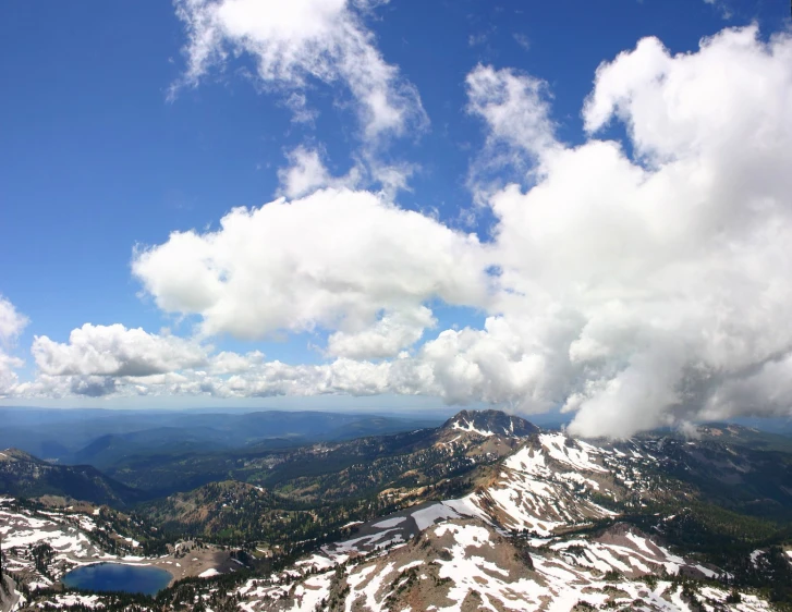 clouds hovering over mountains are shown with a blue sky