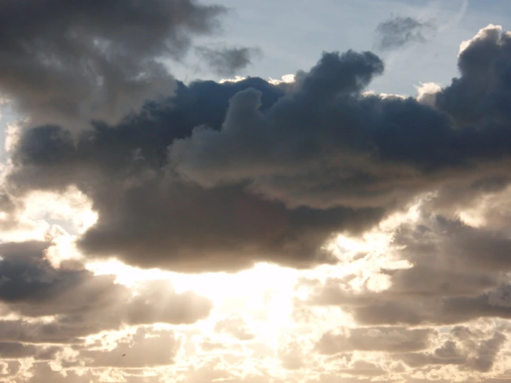 a bird flying in the sky with some clouds