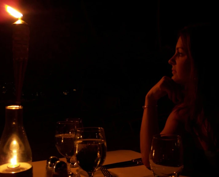 a woman sitting at a table with some wine glasses