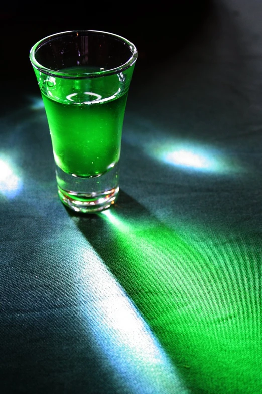 a green beverage in a small cup on a table