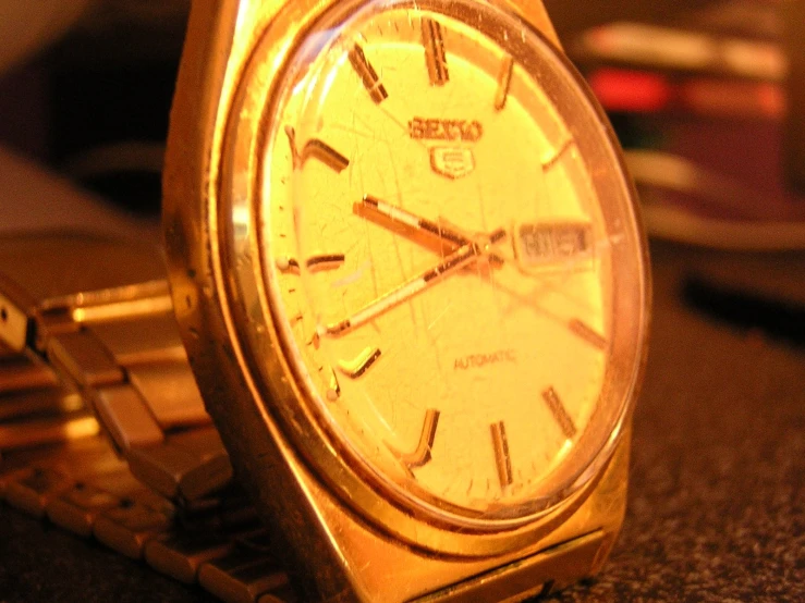 a gold watch sitting next to a gold chain