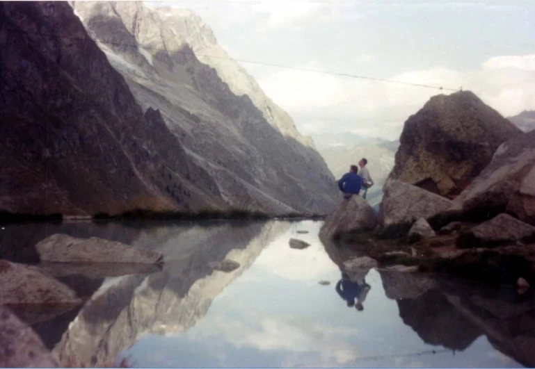 two people are on top of rocks by the water