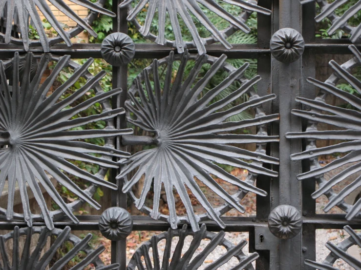 four small circular metal flowers on a fence