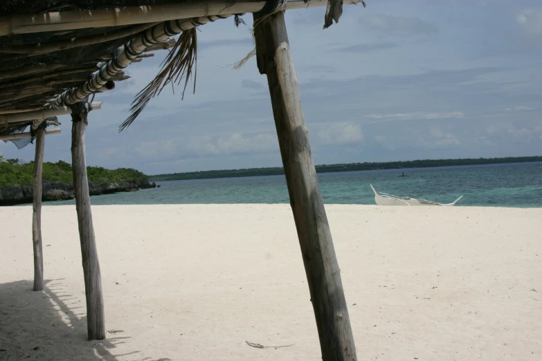 a boat on a beach with a wooden gazebo