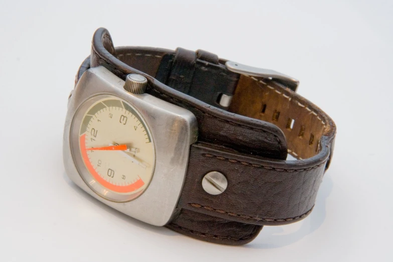 a small metal watch with a brown leather band