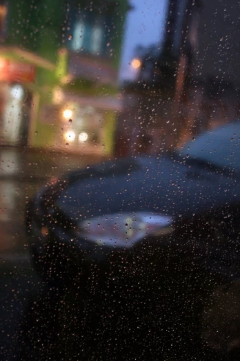 rain drops on a window that has cars and lights