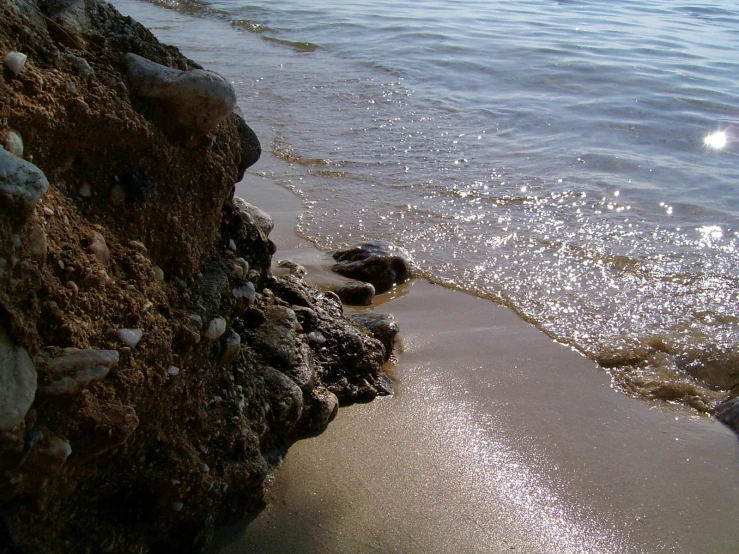 the tide washes up on the beach by rocks and water