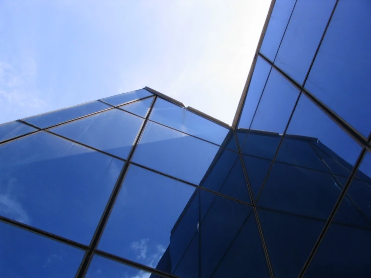 the top portion of two buildings, reflecting the sky