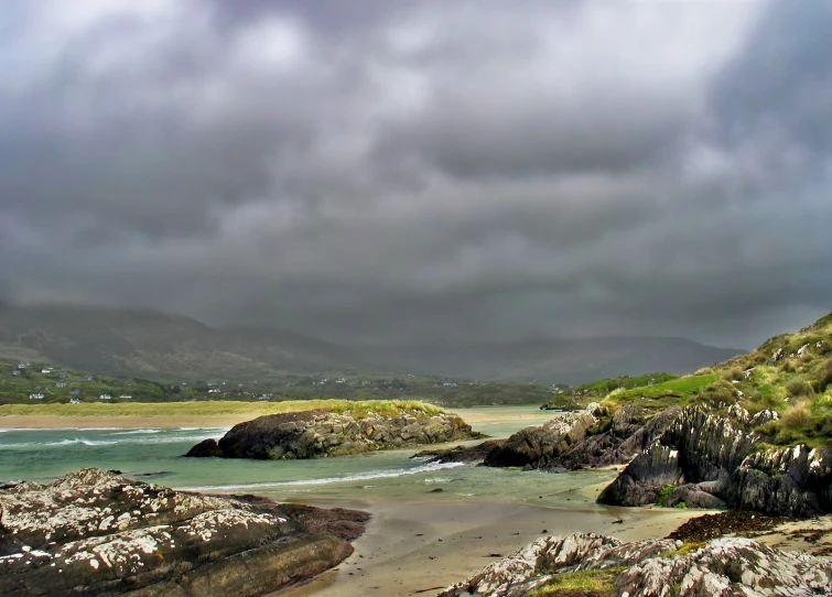 the water has a sandy shore under a cloudy sky