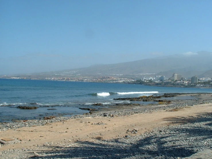 a sandy beach with mountains in the distance