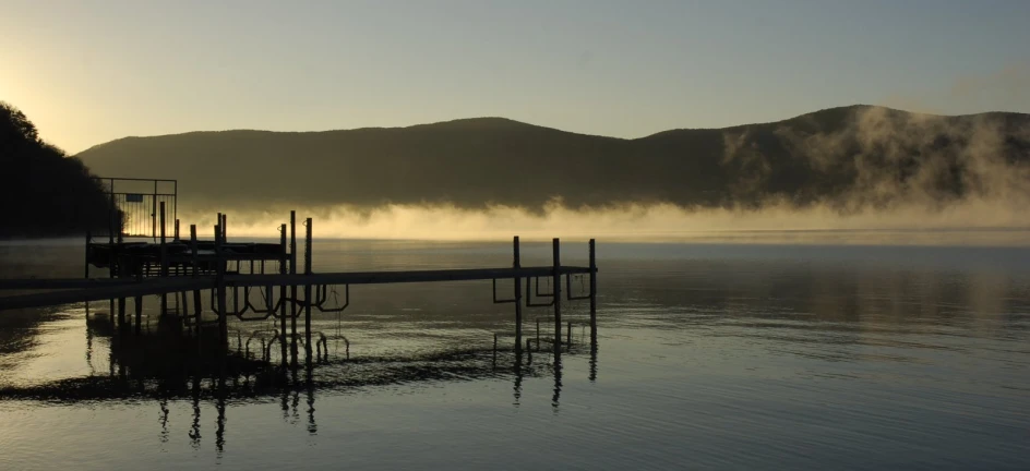 a lake with steam rising from it at sunset