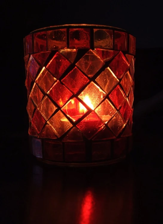 an ornate, colorfully shaped candle sits in the dark
