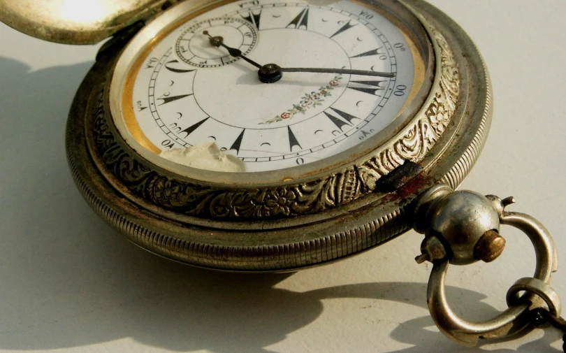 an antique pocket watch sits on top of the table