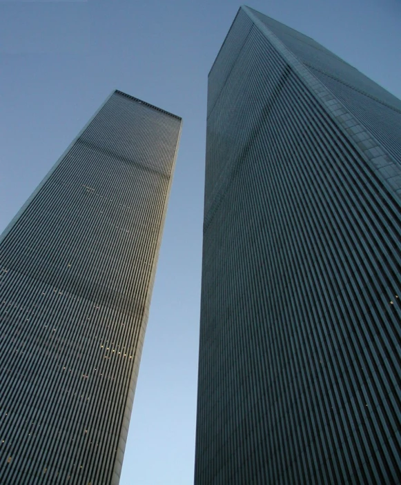 two tall buildings one is blue with the other is grey