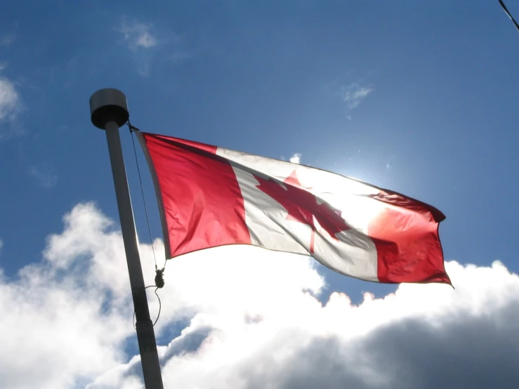 the canadian flag is flying high against a bright blue sky