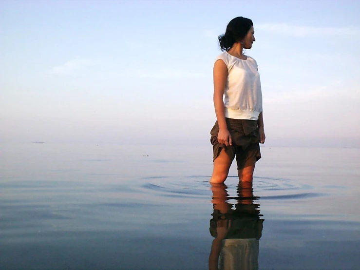a woman standing in water looking down at the ground
