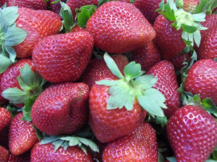 a large pile of fresh strawberries close to each other