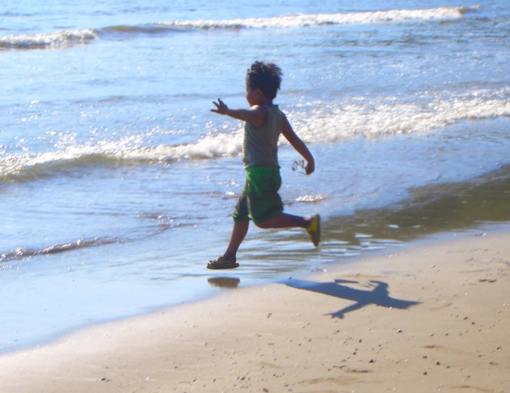 a boy plays on the beach in the water